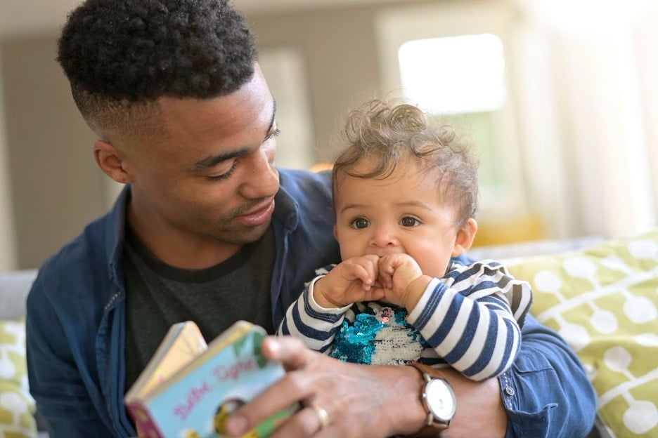 A young dad reading to his baby.