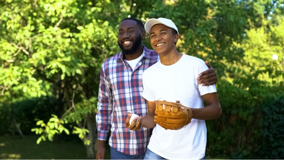 A foster child and parent playing baseball.